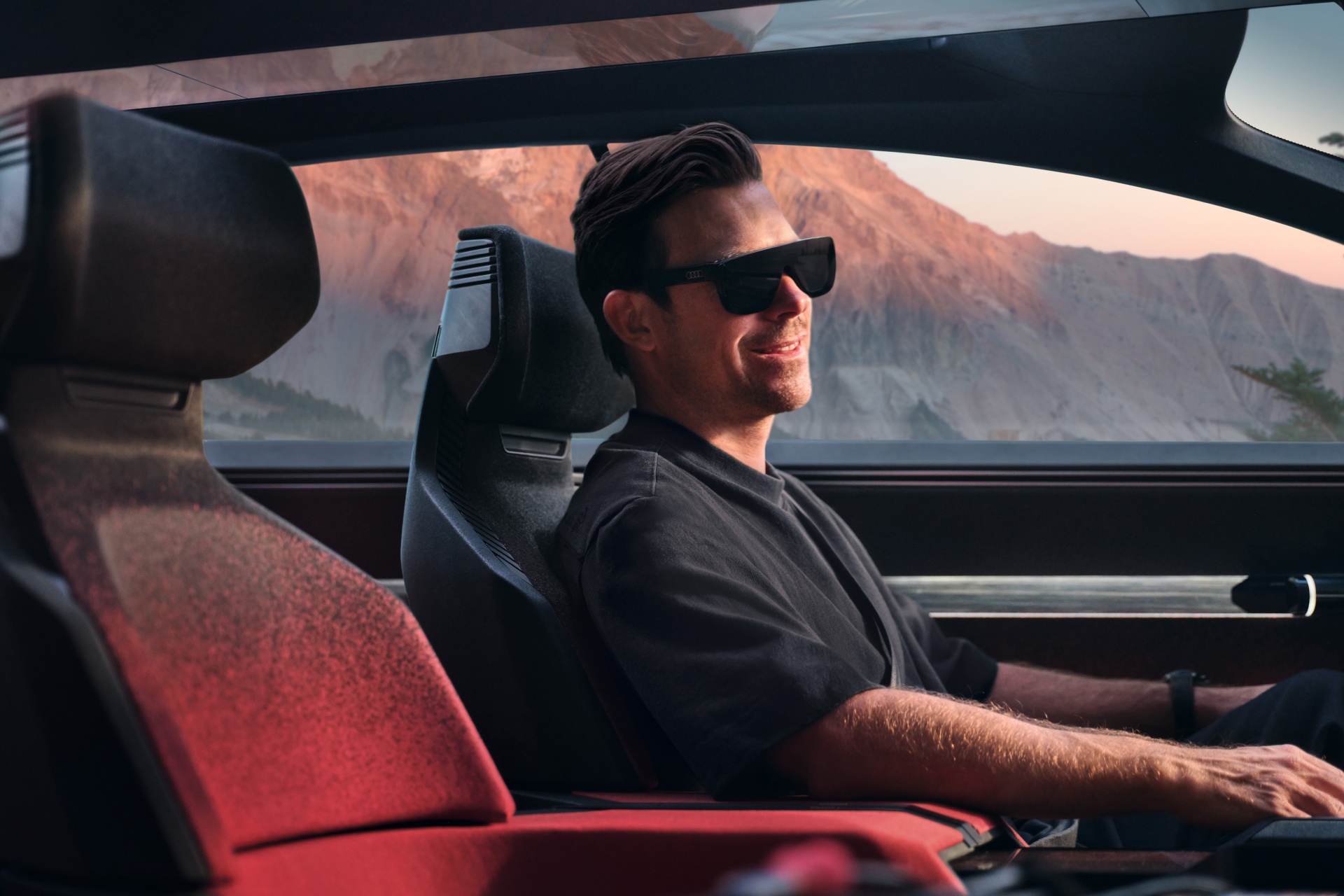 Hayden Cox is sitting in the Audi activesphere concept wearing AR glasses.